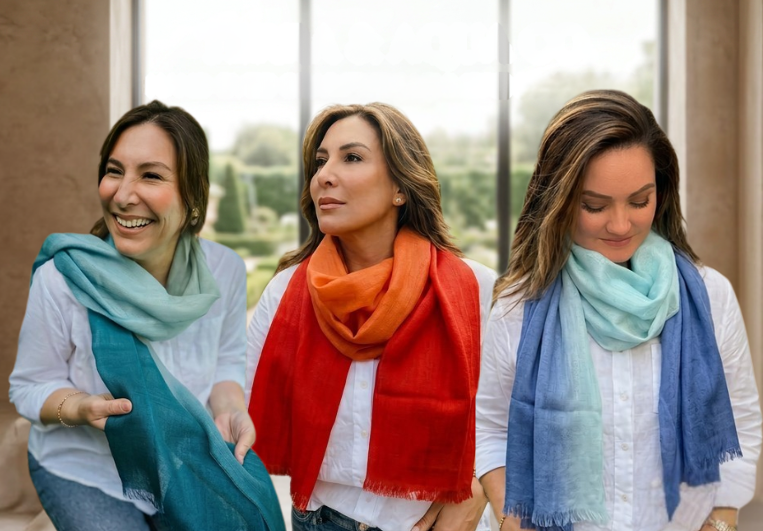 Three women wearing colorful silk and alpaca scarves standing outdoors with a blurred background